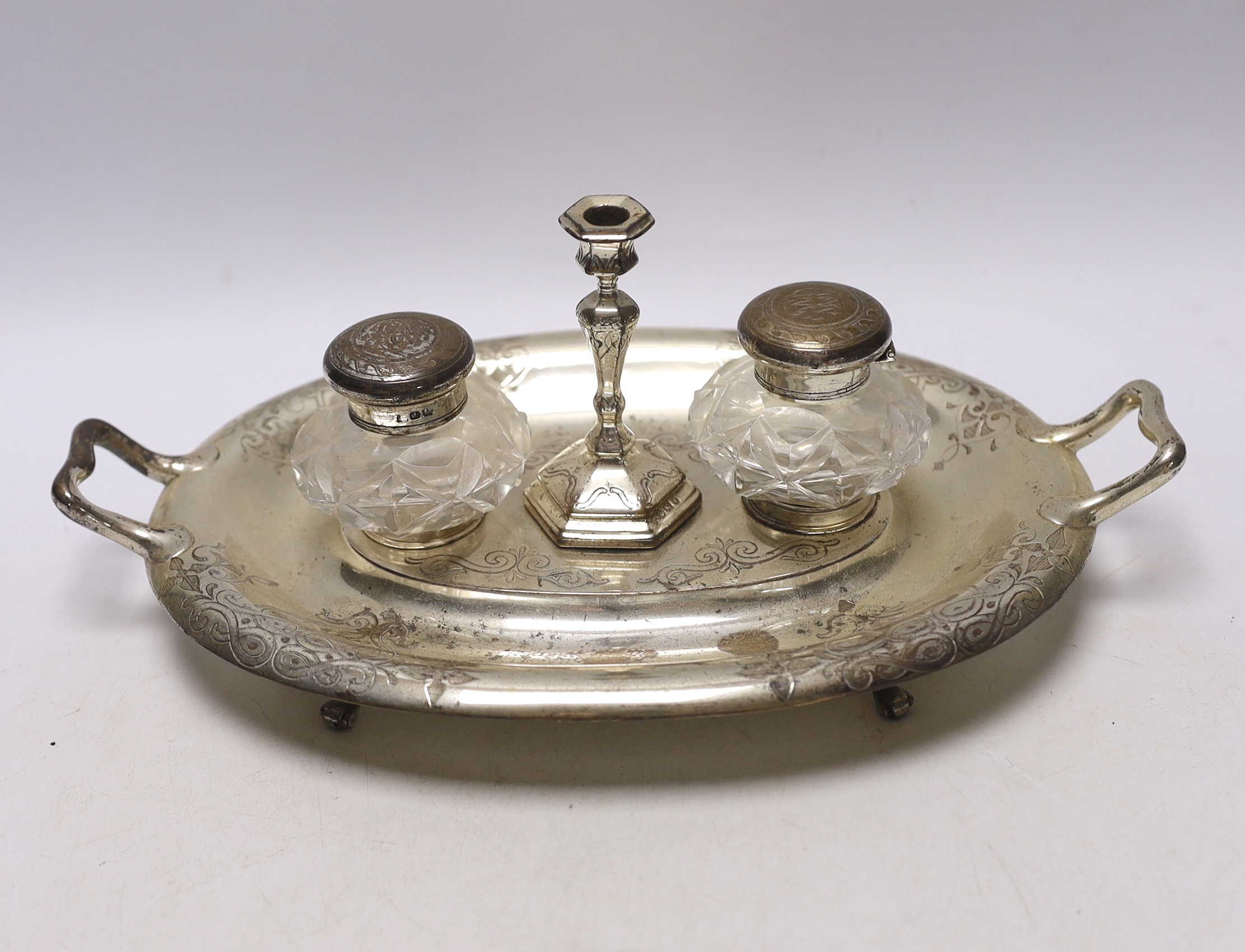 A Victorian engraved silver oval two handled inkstand, with two mounted glass wells and a taperstick, on four scroll feet, Henry Wilkinson & Co Ltd, 1858, 30.4cm over handles, 15.6oz.